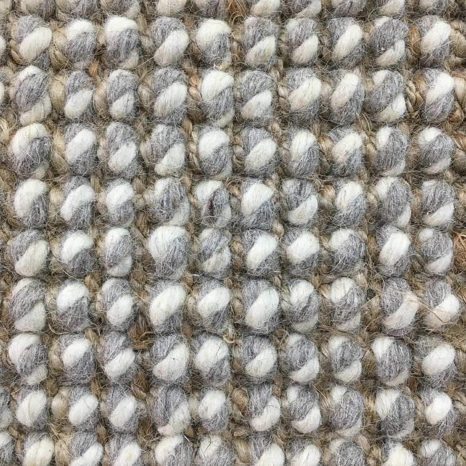 Thick gray and white wool-blend yarns form a textured grid, highlighting superior craftsmanship and natural fibre durability.