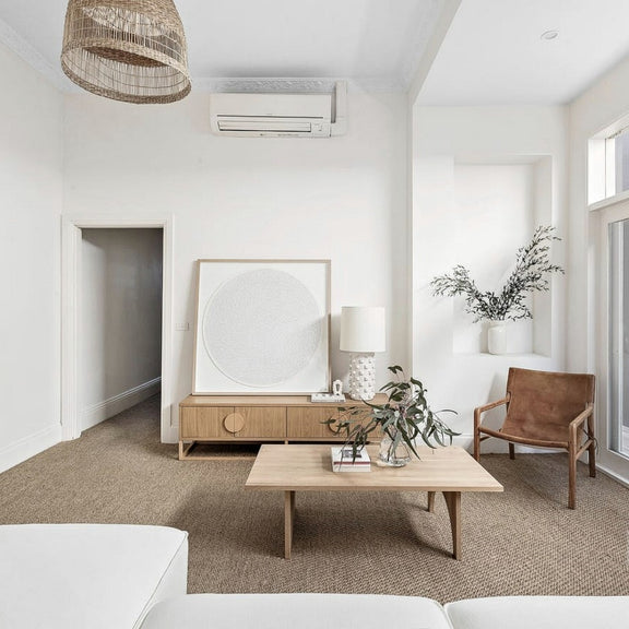 A serene living room styled with neutral hues, natural wood furnishings, and a textured sisal rug on polished timber floors.