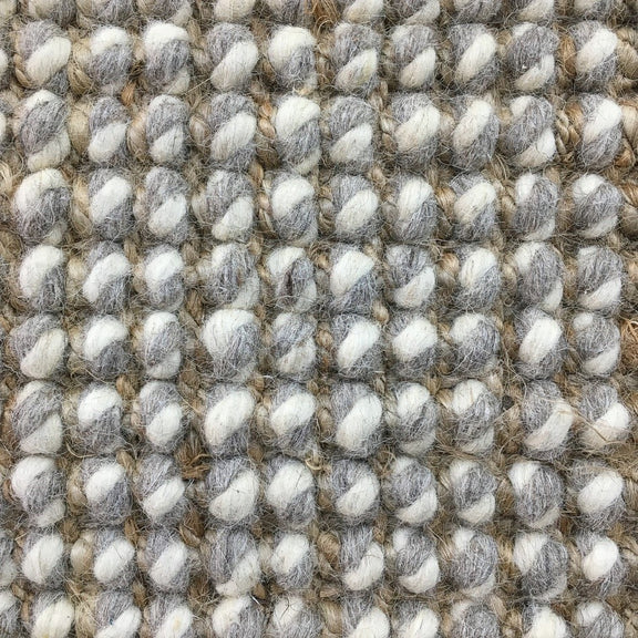 Thick gray and white wool-blend yarns form a textured grid, highlighting superior craftsmanship and natural fibre durability.