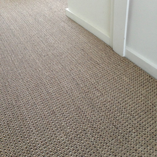 Detail of textured sisal carpet in Autumn Slate, meeting two crisp white walls—showcasing refined natural fibre craftsmanship.