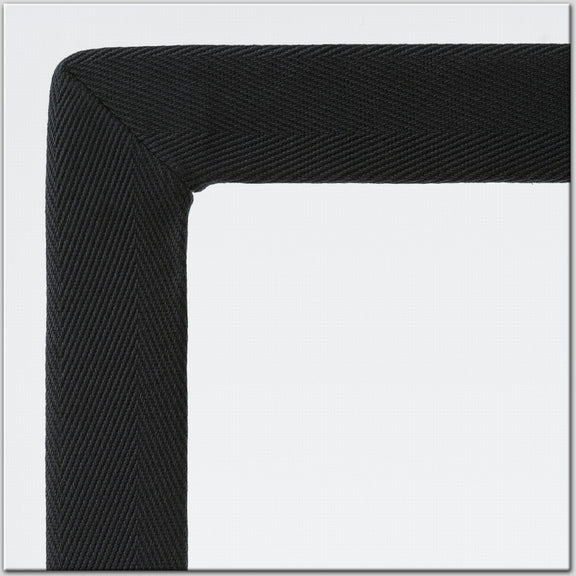Detail of a black textured cotton and linen frame corner on a light grey backdrop, highlighting refined craftsmanship.