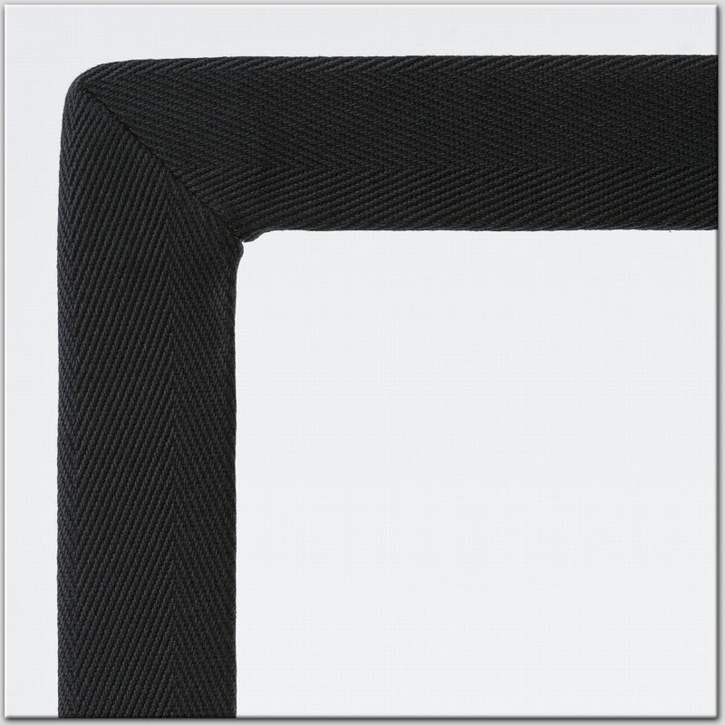 Detail of a black textured cotton and linen frame corner on a light grey backdrop, highlighting refined craftsmanship.