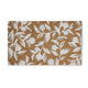 Elegant doormat in natural brown with a crisp white leafy branch motif, displayed on timber flooring in a curated entryway.