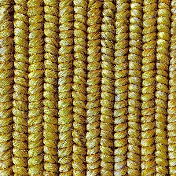 Vertical strands of richly textured, golden yellow natural fibre rope showcase artisanal weaving and refined craftsmanship.