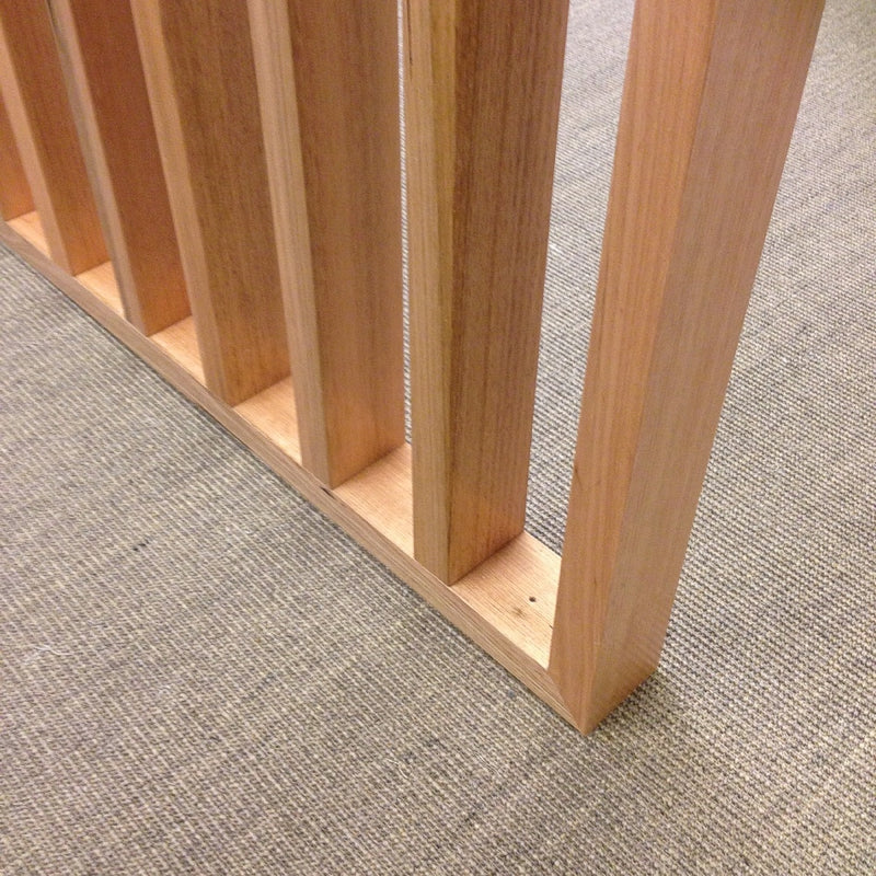 Vertical wooden slats rise from a pale grey floor, beautifully accented by fine ribbed granite-hued sisal for a refined finish.