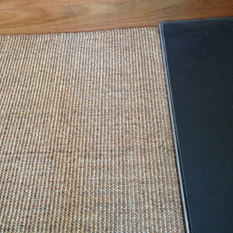 Fine ribbed sisal flooring in a deep charcoal hue, set against a smooth wooden baseboard, highlighting natural texture and elegance.