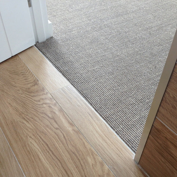 Seamless transition from warm timber flooring to refined ribbed sisal carpet, highlighting craftsmanship and timeless design.