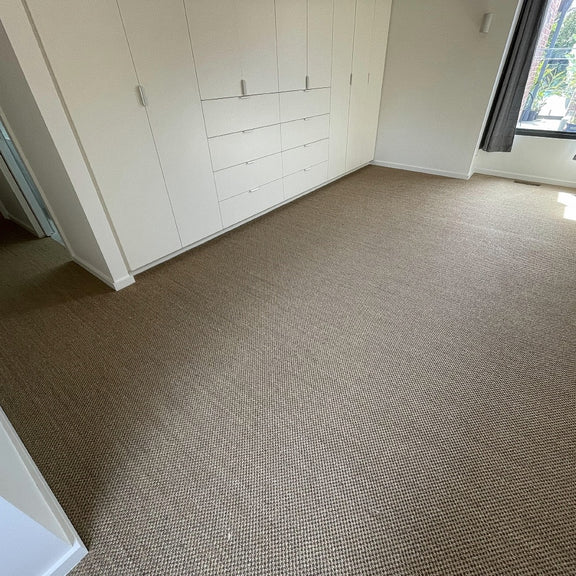 Sunlit room featuring durable, natural sisal flooring, streamlined built-in wardrobes and a large window enhancing the serene space.