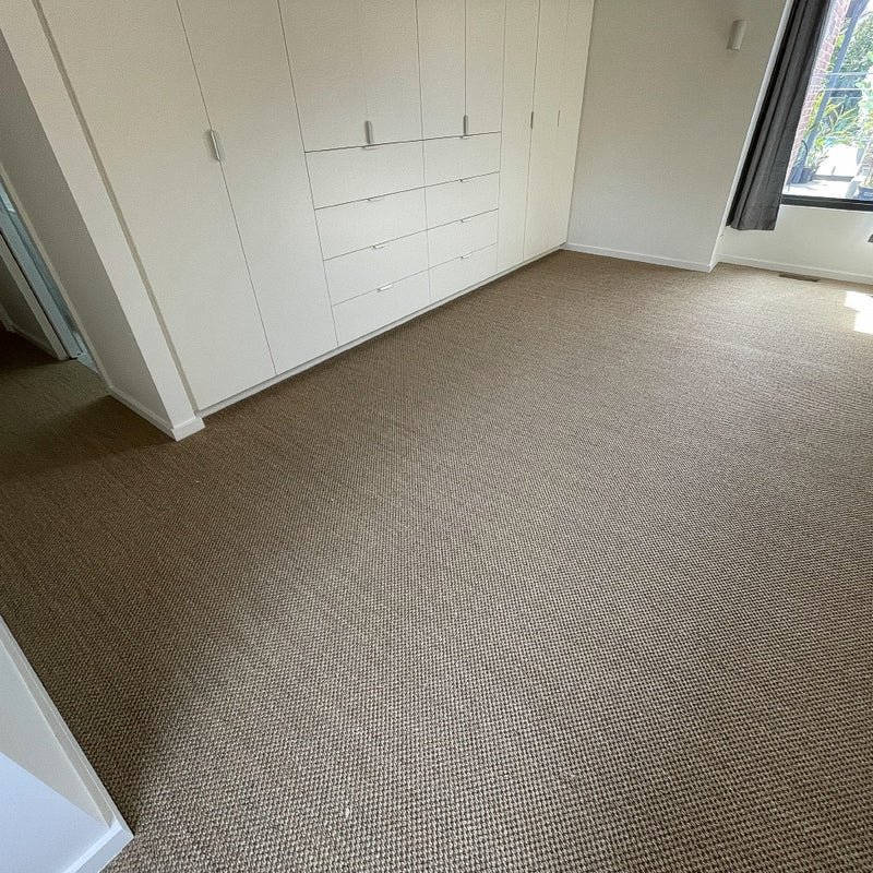 Sunlit room featuring durable, natural sisal flooring, streamlined built-in wardrobes and a large window enhancing the serene space.