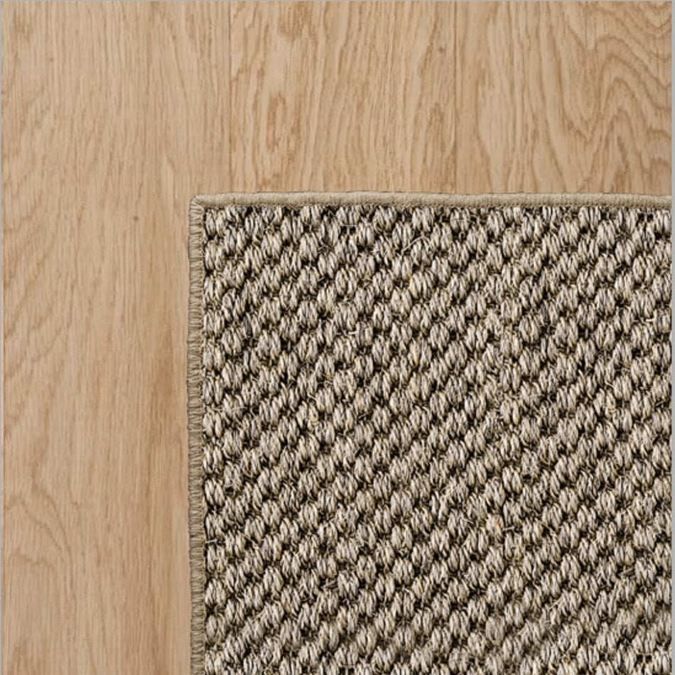 Overlock border rug in a natural fibre, showcased on light timber flooring for an elegant, refined interior finish.
