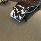 A cowhide and metal chaise lounge sits atop rich, textured slate-grey sisal flooring in a refined, contemporary living space.