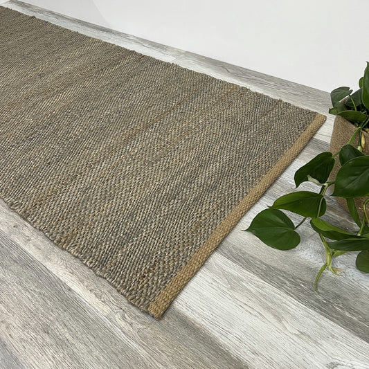 A frost grey runner sits on pale timber floors next to a leafy green plant in a clay pot, styled in a bright, modern interior.