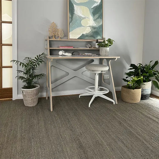 A frost grey jute rug anchors a refined, minimalist workspace with a sleek desk, modern chair and abstract wall art in a city apartment.