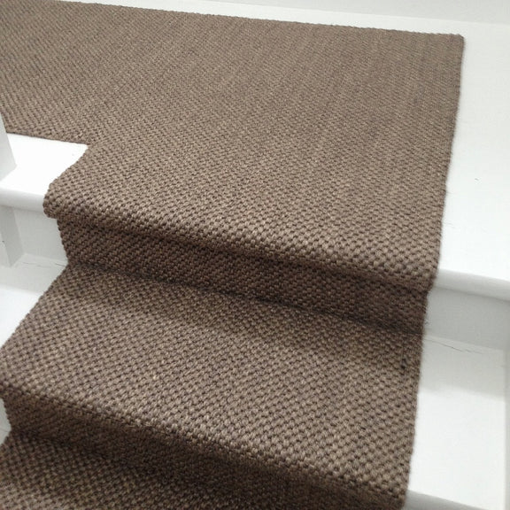 A natural sisal runner in a fine granite weave lines each white stair edge, elevating the serene, crafted home interior.