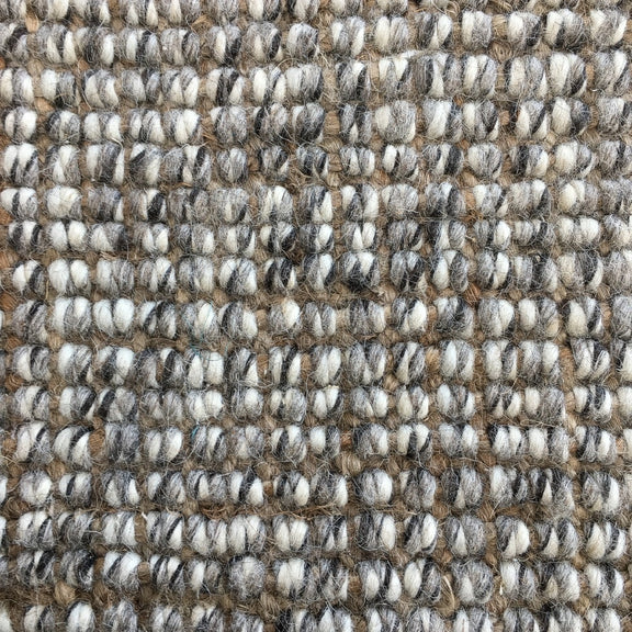 Thick, textured loops of beige, white, brown and gray wool and jute fibres create a refined, natural woven surface.