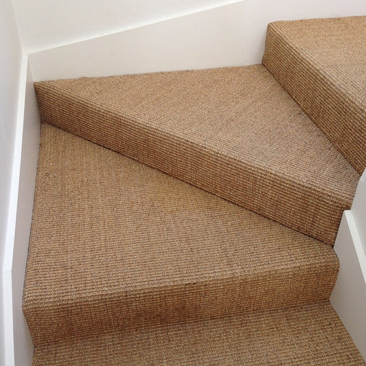 Elegant winder stairs with triangular steps in heavy ribbed sisal, framed by crisp white walls for a refined, natural look.