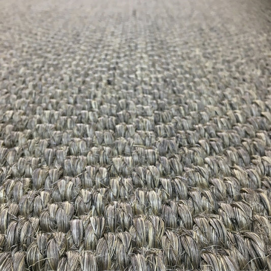 Detailed view of tightly woven beige and grey sisal fibers, highlighting rich texture and craftsmanship of premium natural flooring.