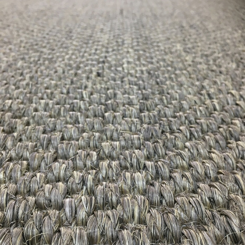 Detailed view of tightly woven beige and grey sisal fibers, highlighting rich texture and craftsmanship of premium natural flooring.