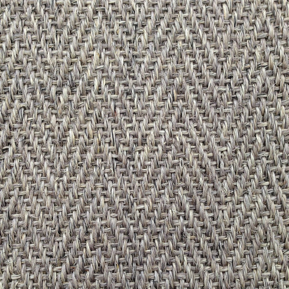 Detailed view of herringbone sisal carpet in soft beige and grey, highlighting refined texture and quality natural fibres.