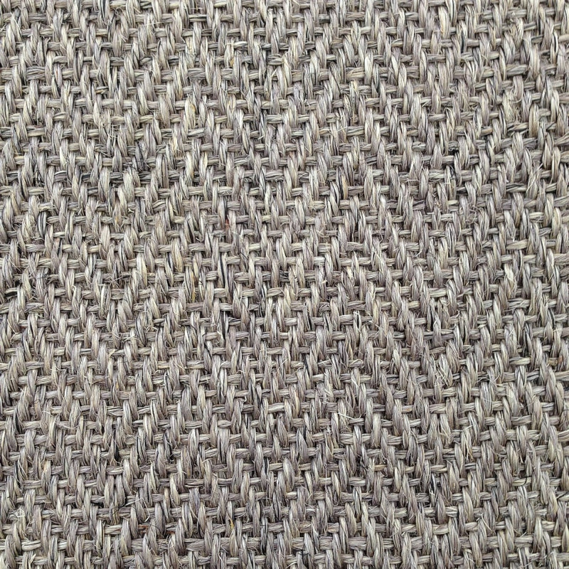 Detailed view of herringbone sisal carpet in soft beige and grey, highlighting refined texture and quality natural fibres.
