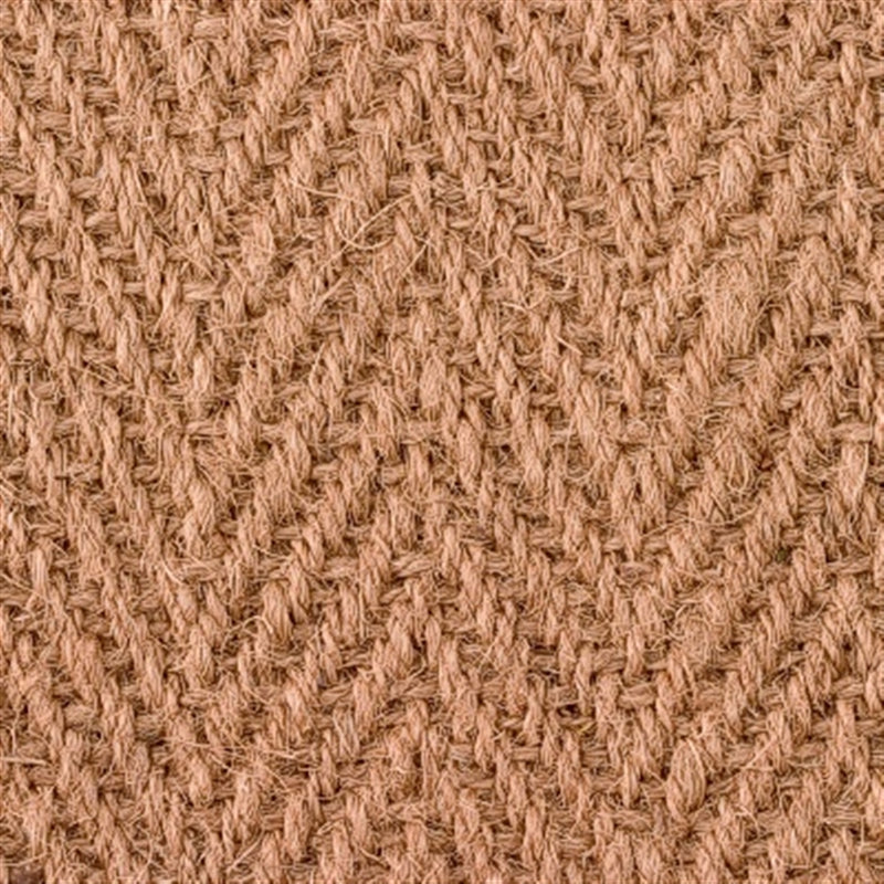 Detailed view of a herringbone coir rug, showcasing handwoven jute texture and warm natural brown fibres.