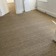 Elegant herringbone seagrass carpet enhances a bright, airy room with white walls, crisp trim, doorways and natural light.