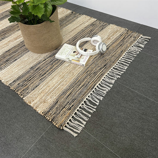 A sophisticated natural fibre runner set on a smooth grey floor, styled with a leafy plant, headphones and a closed book.