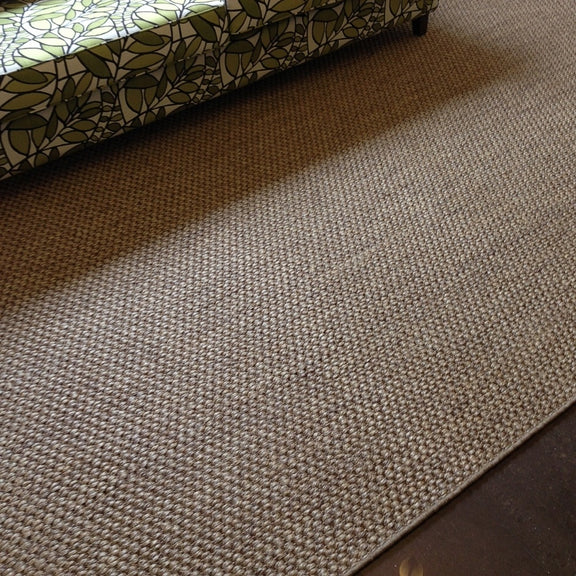 A green and white sofa pairs with a rustic sisal rug on dark wood floors in a thoughtfully styled, modern living space.