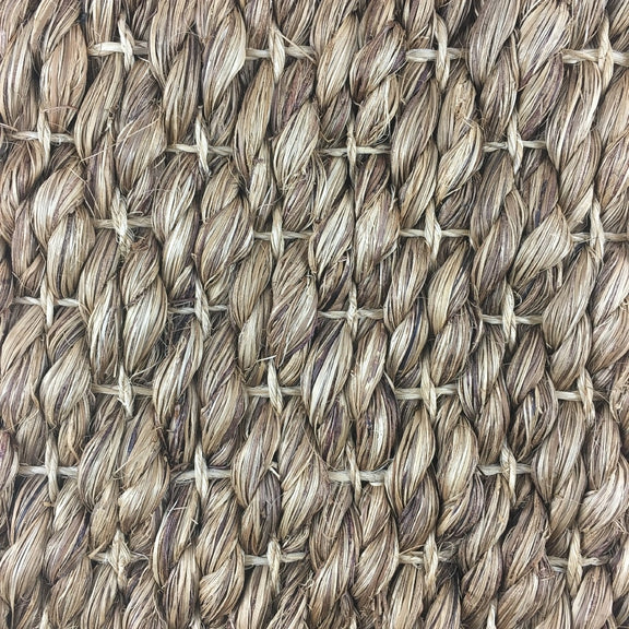Thick, twisted natural abaca fibers woven in a refined crisscross pattern, showcasing artisanal craftsmanship and durability.