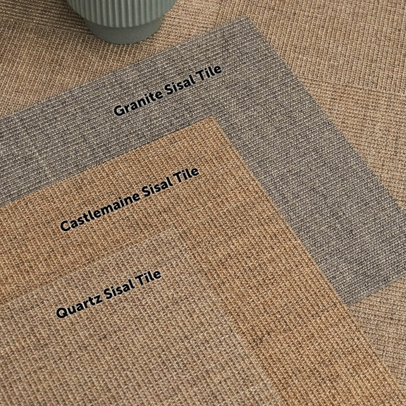 Three natural sisal tiles are arranged on a textured surface with a round ceramic pot, showcasing refined, sustainable fibres.