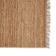 Elegant close-up of a handwoven jute rug with natural fringe, highlighting rich texture and artisanal craftsmanship on white.