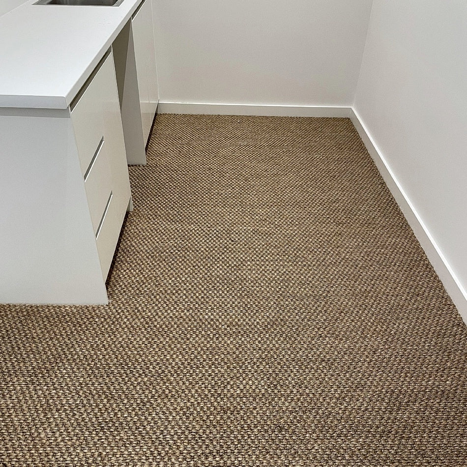 A bright, inviting corner with a white countertop and an elegant sisal rug, highlighting natural texture and refined design.
