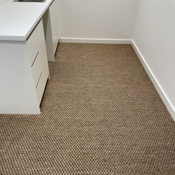 A bright, inviting corner with a white countertop and an elegant sisal rug, highlighting natural texture and refined design.