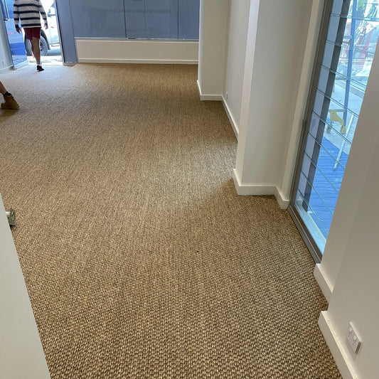 Natural sisal flooring elevates a bright room with white walls, large windows and refined, sustainable interior styling.