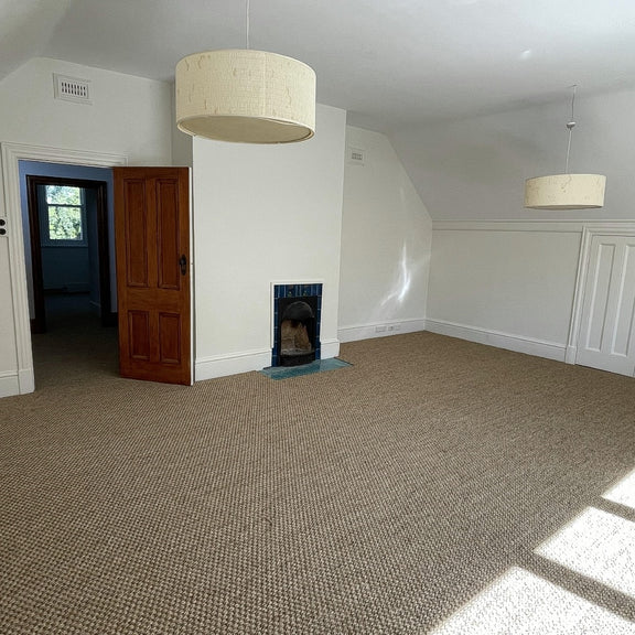 Sunlit living space featuring a woodland sisal rug, elegant lighting, wood fireplace, and natural timber door in a styled interior.