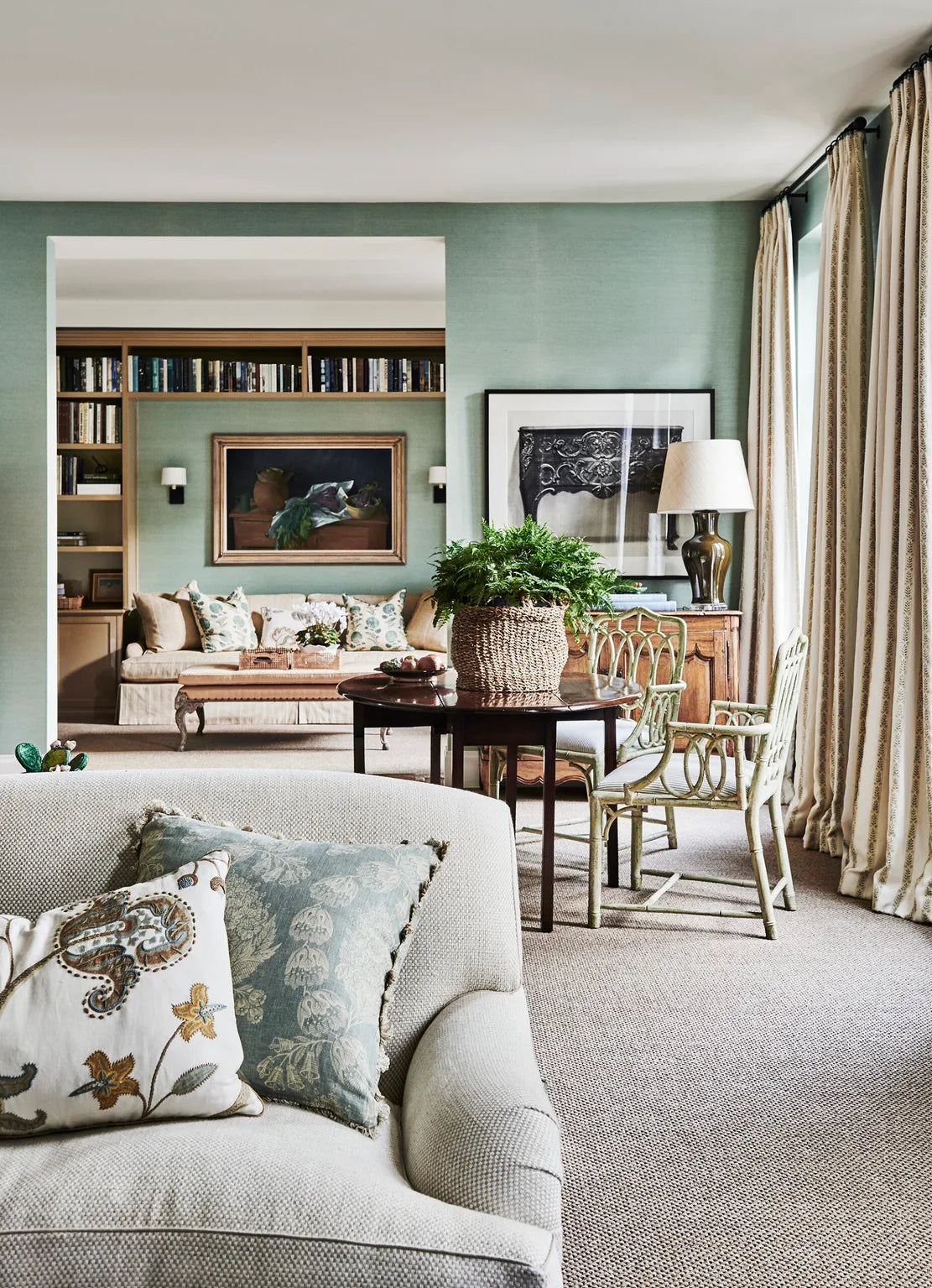 Stylish living room featuring pastel walls, patterned pillows, a lush potted plant and a premium natural fibre rug underfoot.