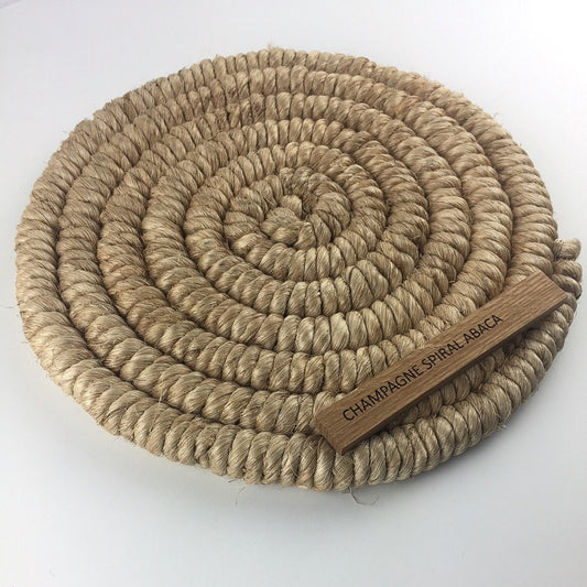 Champagne-toned abaca mat with intricate spiral weave braid, showcasing fine natural fibres and refined craftsmanship.