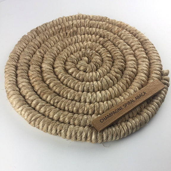 Champagne-toned abaca mat with intricate spiral weave braid, showcasing fine natural fibres and refined craftsmanship.