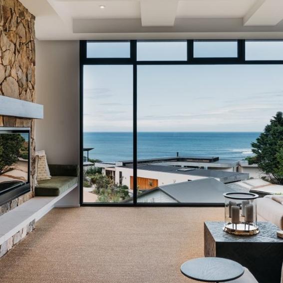 Sunlit living room with elegant natural fibre flooring, expansive windows and ocean views, styled for modern Australian interiors.