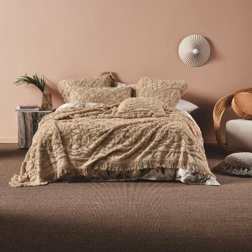 Beige textured bedding set on a bed in a bedroom with a decorative wall clock.