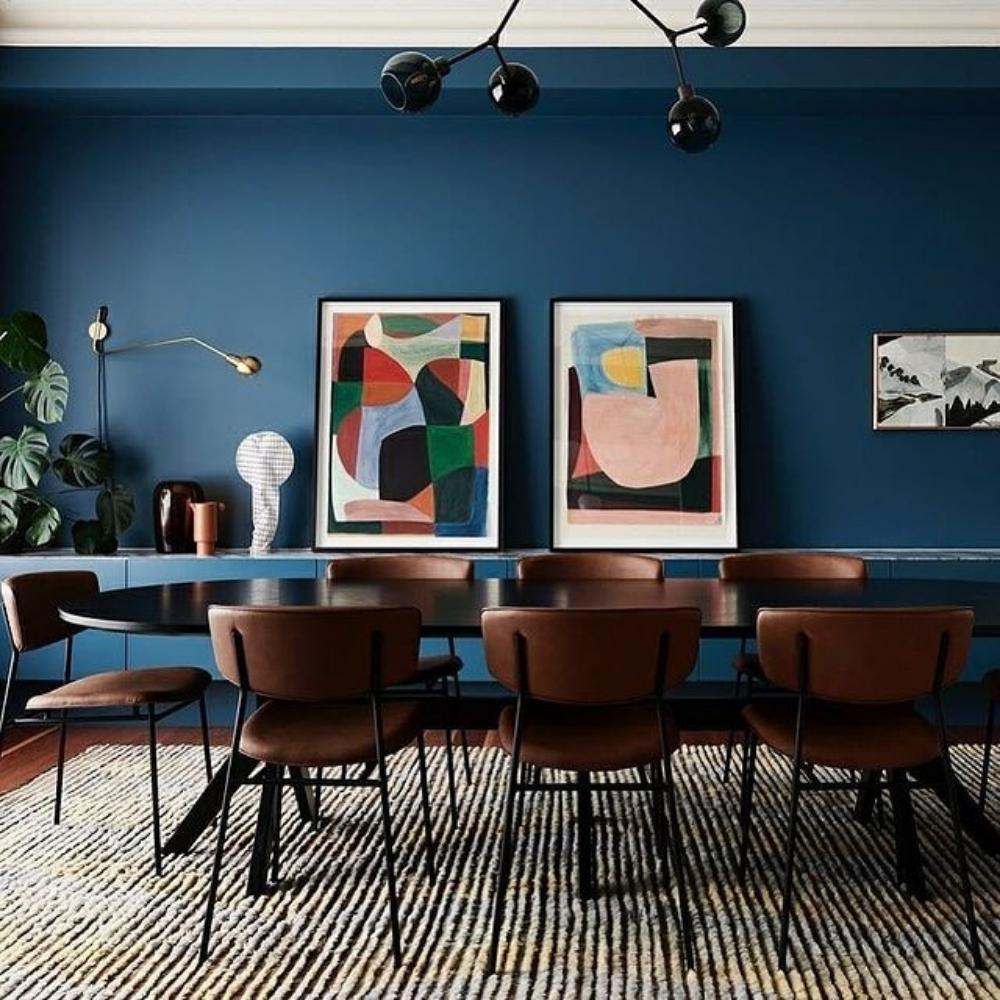 Elegant dining room featuring soft brown chairs, a sleek table, abstract blue wall art and a handwoven natural fibre rug.