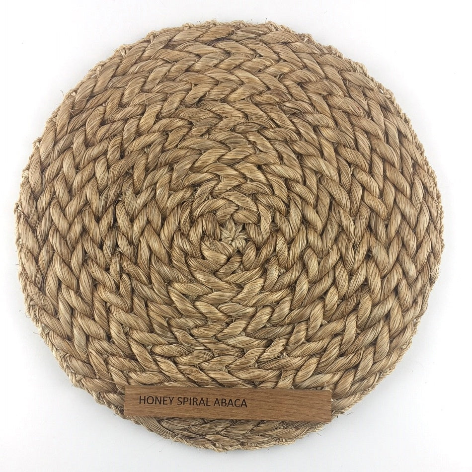 A finely woven, round abaca placemat in a warm honey tone, showcasing natural texture and elegant artisan craftsmanship.
