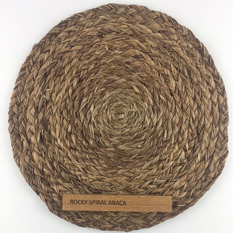 A round abaca placemat with a spiral weave design rests atop a coordinating abaca rug in an elegantly styled interior.