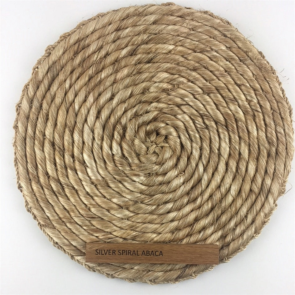 Elegant round placemat crafted from silver-toned abaca, showcasing refined spiral weave and superior natural fibre craftsmanship.