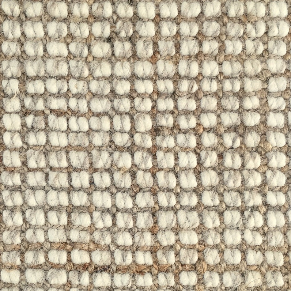 Detail of a wool and jute floor covering with a subtle grid pattern and thick, hand-crafted textured loops in soft natural tones.