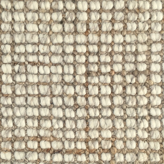 Detail of a wool and jute floor covering with a subtle grid pattern and thick, hand-crafted textured loops in soft natural tones.